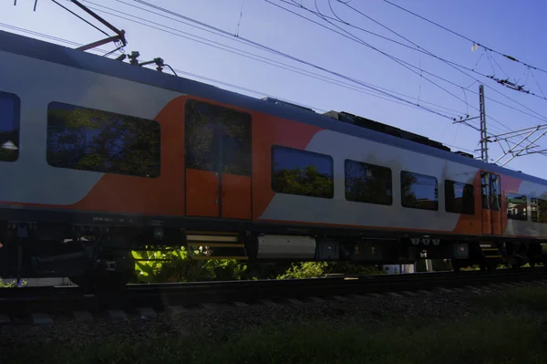 O trem vermelho-cinza varre a cidade resort, o céu é refletido nas janelas — Fotografia de Stock