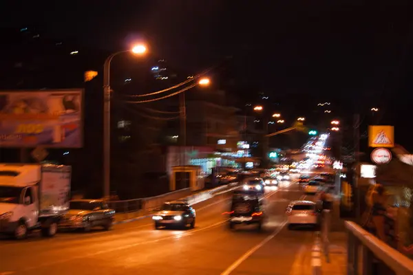 Νυχτερινή οδός - τα αυτοκίνητα οδηγούν κατά μήκος ενός στενού δρόμου. Προβολείς, αυτοκίνητα, δρόμοι, κυκλοφορία. — Φωτογραφία Αρχείου