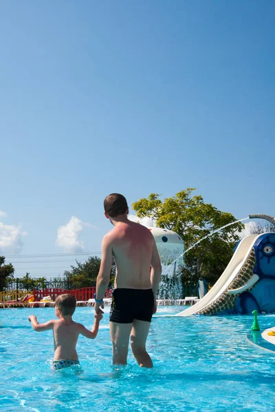 Šťastné batole tří let hraje dohánět svého otce ve venkovním bazénu v aquaparku — Stock fotografie