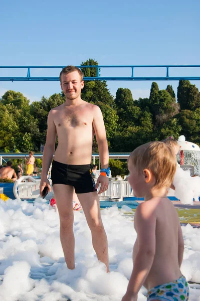 Mladý otec a syn relaxovat na pěnové párty v hotelu — Stock fotografie