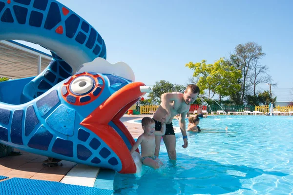 Šťastné batole tří let hraje dohánět svého otce ve venkovním bazénu v aquaparku — Stock fotografie