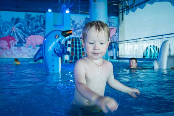 Malý blonďatý chlapec se svým otcem koupat v uzavřeném bazénu aquaparku — Stock fotografie