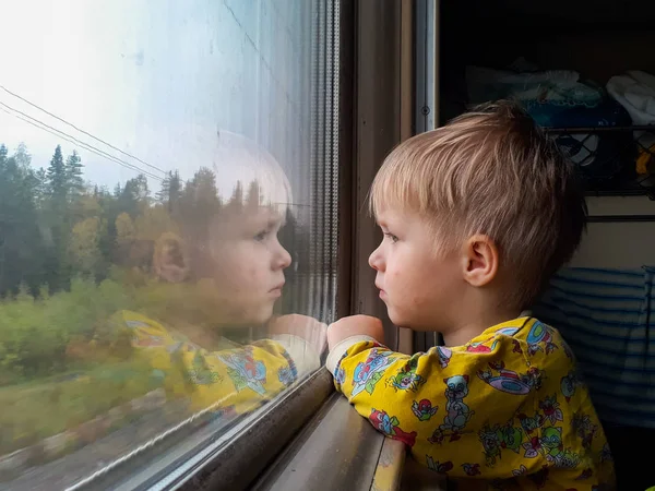 Üç yıllık sarı saçlı küçük bir çocuk trene biniyor, şeker yiyor ve pencereden dışarı bakıyor, arkasında güzel bir sonbahar manzarası uçuyor..