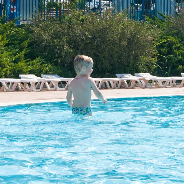 Un bebé rubio feliz de tres años con un abrigo carbonizado está nadando en la piscina infantil — Foto de Stock