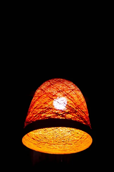 Un abat-jour rétro orange tressé avec une ampoule en bois sur un fond sombre. Détail de l'intérieur. Lumière. Photo verticale conceptuelle — Photo