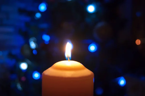 Płonąca pomarańczowa świeca na ciemnym tle z niebieskimi światłami - Boże Narodzenie Sylwester wróżenie mistyczne ezoteryczne romans nastrój miłosny. Zdjęcie poziome, boczne, ostrość lub defokus — Zdjęcie stockowe