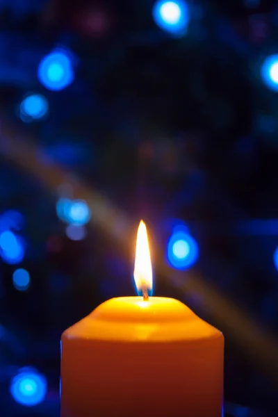 Duża Świeca Pali Się Tle Girlandy Świecącymi Światłami Pionowe Zdjęcie — Zdjęcie stockowe