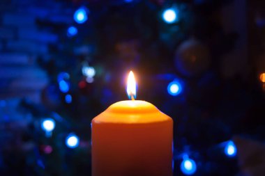 Parlak ışıkları olan bir çelengin arka planında büyük bir mum yanar. Dikey fotoğraf, odak kaybı. Mistik esrarengiz romantizm kehaneti Noel şarkıcılarını vaftiz etme ruh hali.