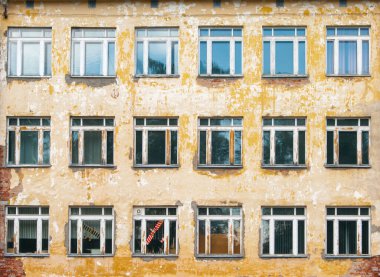 Dekoratif arka plan - duvar, pencereler. Fotoğraf eski okulun turuncu duvarını ve bir tanesinde kırmızı renkte bir oyuncak uçağın görülebildiği birçok pencereyi gösteriyor. Boya ve sıva, binanın duvarlarından parça parça sökülmüş. Tamire ihtiyacım var. Pover.