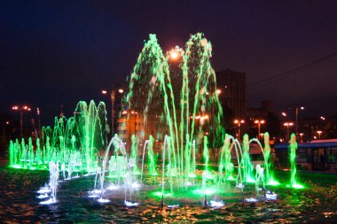 Bahçe düzenleme - koyu mavi bir gece gökyüzüne karşı parlak yeşil ışıklarla aydınlatılmış güzel bir çeşme. Aydınlatma, gece, ışıklar, parlaklık, peri masalı, gerçeküstü, güzellik