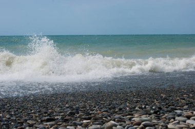 Deniz bir zamanlar endişeliydi. Küçük bir fırtınadan sonra Karadeniz 'in çamurlu suları. Deniz, berrak gökyüzü ve düz ufuk çizgisi, dalga, kumsalda ıslak büyük çakıl taşları.