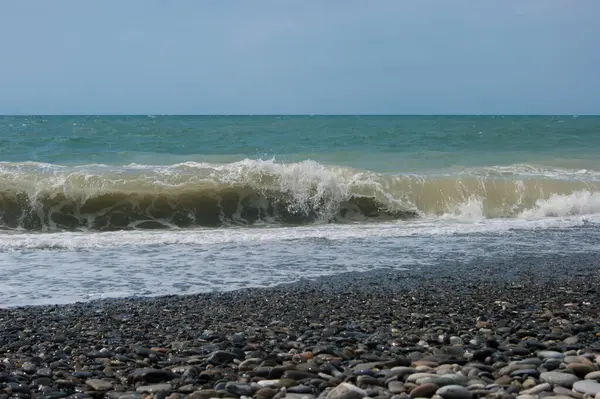 海一度心配している-黒海の小さな嵐の後に少し泥だらけの水。海、澄んだ空と滑らかな水平線、波、ビーチでぬれた大きな小石. — ストック写真