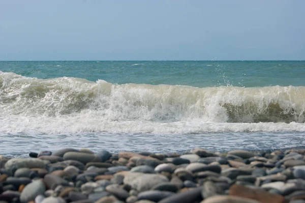 La ola de mar del Mar Negro es una playa de guijarros. Horizonte liso, cielo azul. — Foto de Stock