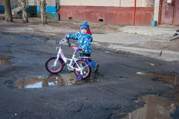 아이는 부러진 도로와 번들에서 바퀴가 자전거와 걷는다 비포장도로 아스팔트 비포장도로 — 스톡 사진