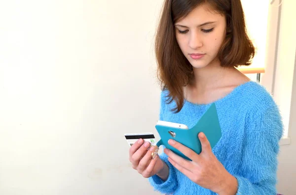 Girl with credit card and telephone. Shopping in the online shop