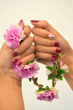 Kısa kırmızı çivi ve işaret parmağı üzerine beyaz manikür