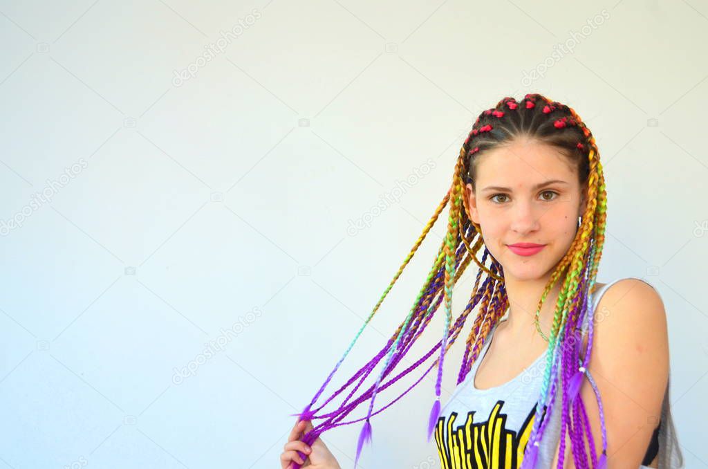 A girl with a fashionable set of multicolored braids Kanekalon. Colored artificial strands of hair. Material for plaiting braids.