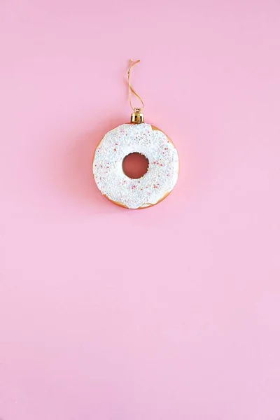 Noel süslemesi, pastel pembe arka planda beyaz kremalı altın rengi donut. Yeni yıl ve Noel yaratıcı konsepti. Üst manzara, düz uzanma.