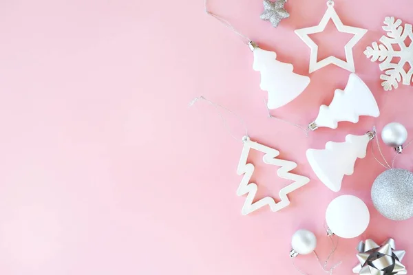 Pastel pembe arka planda beyaz ve gümüş süslemelerin Noel kompozisyonu. Minimalist tatil konsepti. Üst görünüm, metin için kopyalama alanı olan düz uzanma .