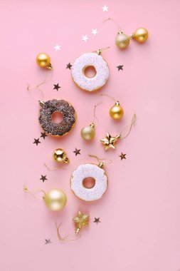 Kar tanelerinin, yıldızların, konfetilerin, baloların, pembe arka planda altın ve beyaz çöreklerin Noel kompozisyon dekorasyonunun en üst görüntüsü. Noel ve Yeni Yıl 'ın kutlu olsun. Dikey, Düz Yatay.