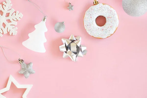 Pastel pembe arka planda beyaz ve gümüş süslemelerin Noel kompozisyonu. Minimalist tatil konsepti. Üst manzara, düz uzanma.