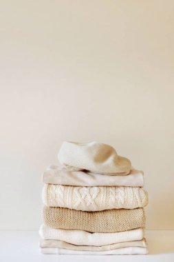 Bir yığın kalın bej örgü kazak. Kapsül dolabı konsepti, rahatlık. Metin için kopyalama alanı ile yakın plan.