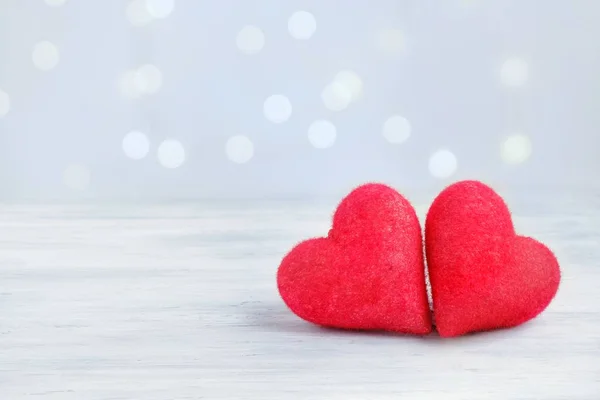 Two closeup love hearts on a wooden table and blurry defocused light bokeh background. Valentine\'s day greeting card. Love and holiday concept. Copy space for text.