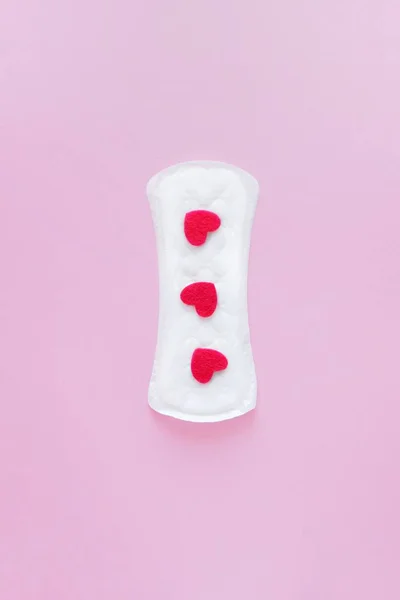 Sanitary pad on a pink background. An alternative choice of feminine hygiene products. Menstrual mothly cycle, means of protection. Vertical, Top view, flat lay.