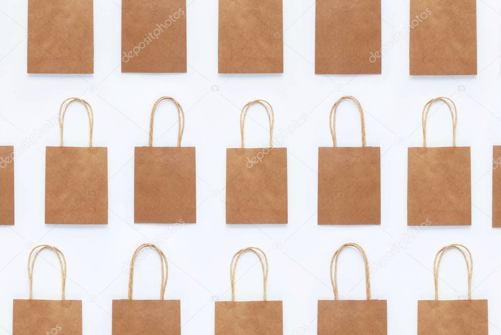 Seamless photo pattern of brown craft packaging bags for shopping on a white background. Concept of zero waste, reasonable consumption, recycling, discounts. Top view, flat lay.