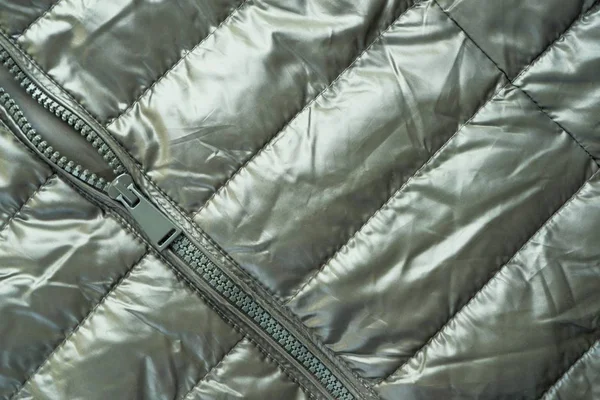 Close-up zipper closure on a light warm jacket of olive color. Warm clothes, accessories for outerwear.