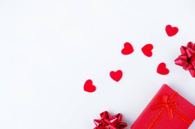 Hediye kutusu, yaylar ve beyaz arka planda kırmızı kalpler. Sevgililer Günü konsepti, aşk, romantizm, tebrikler, tatil. Üst görünüm, düz görünüm, metin için alanı kopyala.
