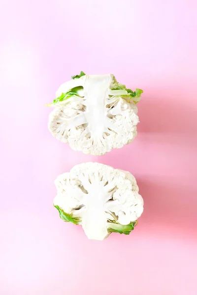 Two half head fresh organic cauliflower on a bright pink background. Minimalistic, natural, lifestyle. Diet concept, healthy food.Creative mocup, Top view, flat lay, copy space for text.