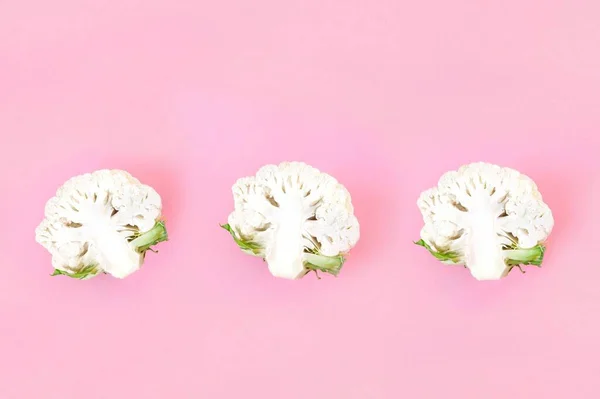 Pembe pastel arka planda üç yarım karnabahar. Sağlıklı gıda konsepti, taze sebzeler, diyet, yemek blogu. Üst görünüm, metin için kopyalama alanı olan düz uzanma.