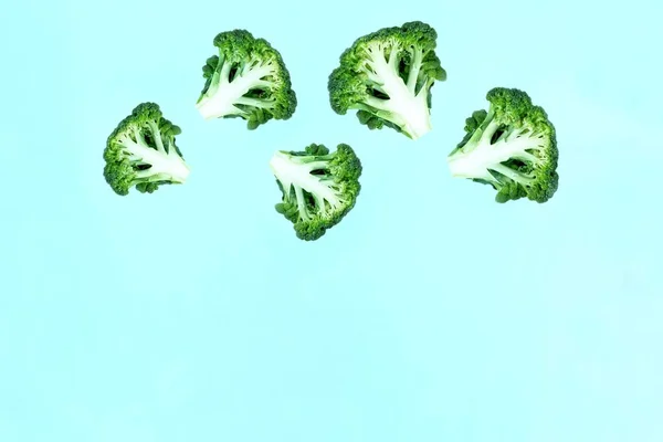 青い背景に高くそびえる緑のブロッコリーのスライスを落下 空飛ぶ食べ物 緑の野菜 野菜のパターンの概念 テキストのコピースペース — ストック写真