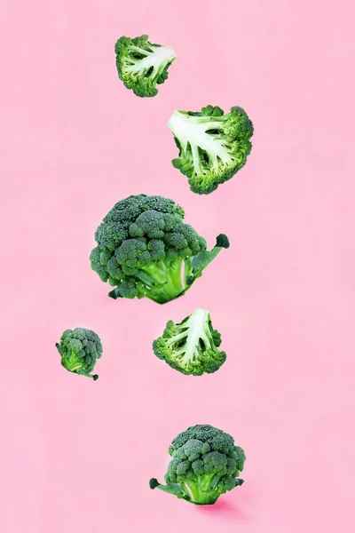 ピンクの背景に高くそびえる緑のブロッコリースライスを落下 空飛ぶ食べ物 緑の野菜 野菜のパターン 食品ブログの概念 テキストのコピースペースの垂直 — ストック写真