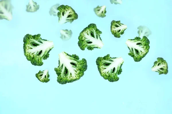 飞的绿花椰菜片蓝色背景 飞行食品 绿色蔬菜 膳食食品 蔬菜的概念 文本的复制空间 — 图库照片