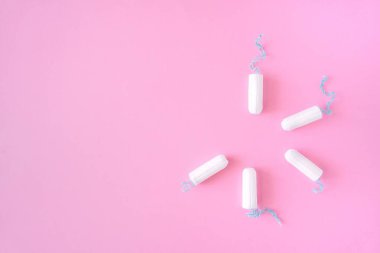 Pembe arka planda birkaç beyaz hijyenik tampon bir daire çiziyor. Aylık adet döngüsü, koruyucu ekipmanlar. Üst görünüm, düz görünüm, metin için alanı kopyala.