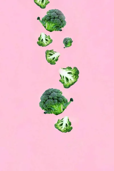 Vallende Groene Broccoli Plakjes Een Roze Achtergrond Concept Van Vliegen — Stockfoto