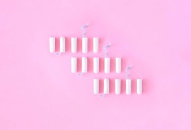 Pembe arka planda dikey sırada duran beyaz hijyenik tampon deseni. Adet döngüsü, koruyucu ekipmanlar, kadın hijyeni. Üst görünüm, düz görünüm, metin için alanı kopyala.
