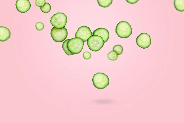 Flying green slices of fresh cut cucumber on a pink background. Vegetables pattern, flying food concept, green vegetables, diet food, blog food. Copy space for text.