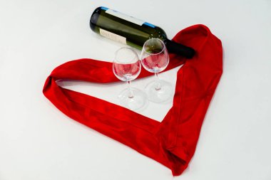 Şarap kadehleri ve kırmızı kurdeleyle süslenmiş şarap şişesi.
