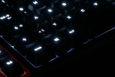 Gecenin karanlığında anahtar logolarının hafif bir parıltısıyla aydınlatılmış klavye.