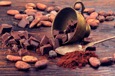Koyu çikolata, kakao tozu ve kahve çekirdekleri ahşap bir masa üzerinde kırık