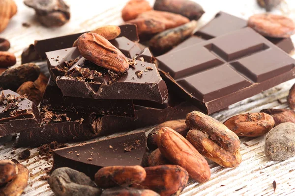 Broken dark chocolate, cocoa powder and coffee beans on a wooden table