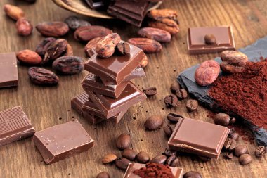 Koyu çikolata, kakao tozu ve kahve çekirdekleri ahşap bir masa üzerinde kırık