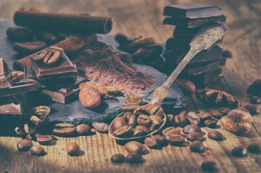 Koyu çikolata, kakao tozu ve kahve çekirdekleri ahşap bir masa üzerinde kırık