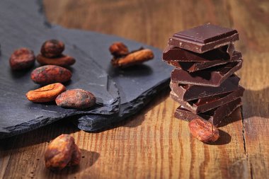 Koyu çikolata, kakao tozu ve kahve çekirdekleri ahşap bir masa üzerinde kırık