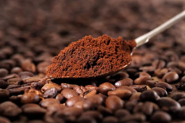 Coffee beans pile on the background of ground coffee