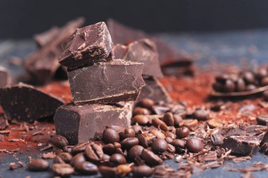 Koyu çikolata, kakao tozu ve kahve çekirdekleri ahşap bir masa üzerinde kırık