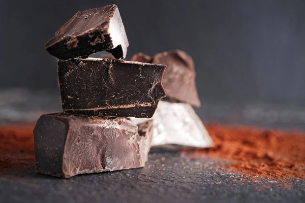 Koyu çikolata, kakao tozu ve kahve çekirdekleri ahşap bir masa üzerinde kırık